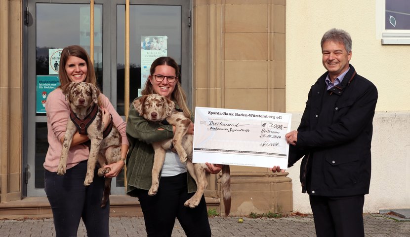 Die DJHN-Mitarbeiterinnen Franziska Straub mit Hündin Mila (links) und Mareike Brecht mit Rüde Paul (Mitte) bekommen von Hartmut Hespelt, Leiter der Sparda-Filiale in Heilbronn, den Spendenscheck überreicht.